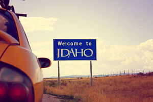 Car next to a street sign that says "Welcome to Idaho"